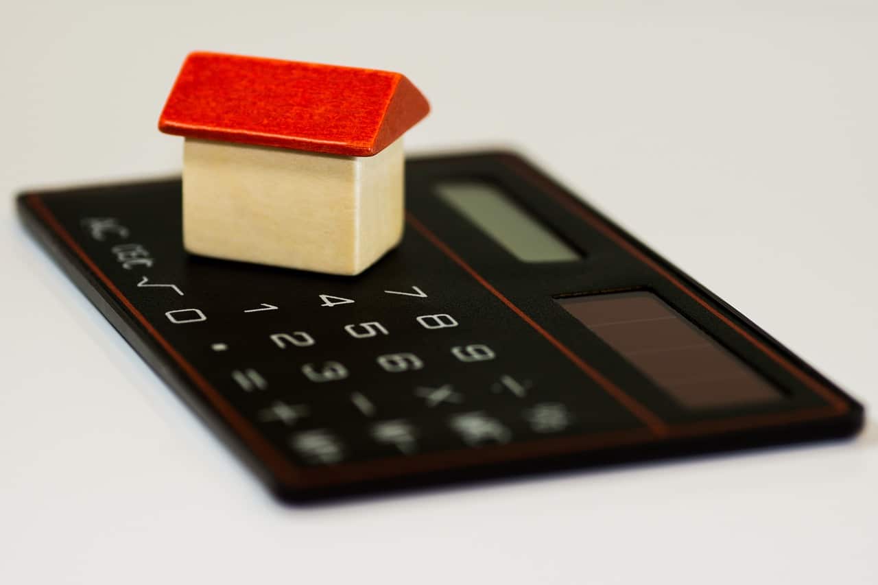 Cálculos que afectan a la hipoteca Casa de madera encima de una calculadora